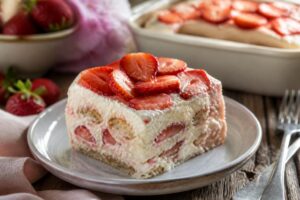 Tiramisù alle fragole cremoso in una coppetta trasparente, con fragole fresche a fette e crema al mascarpone soffice, fotografato dall'alto su un piano di marmo chiaro